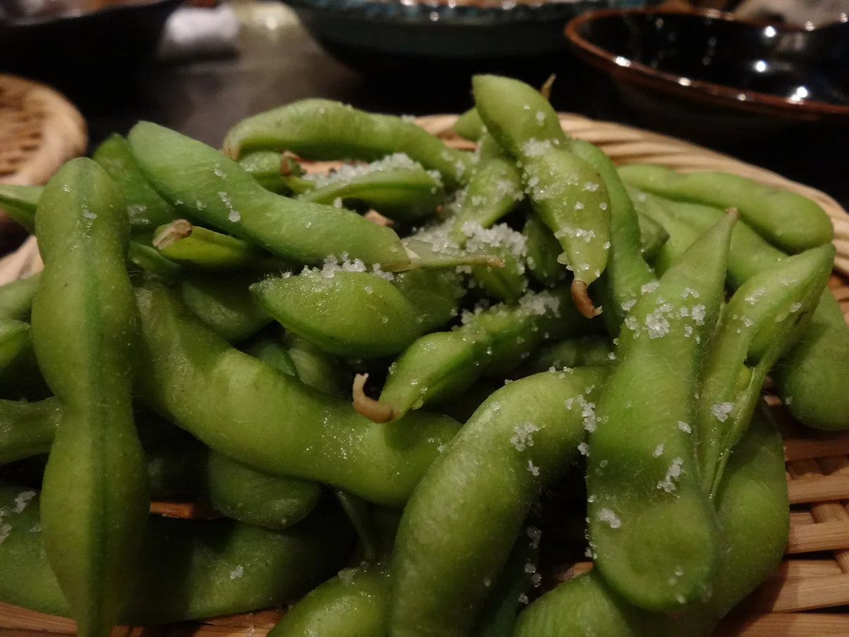 Salted edamame pods in a bamboo basket at a Japanese restaurant